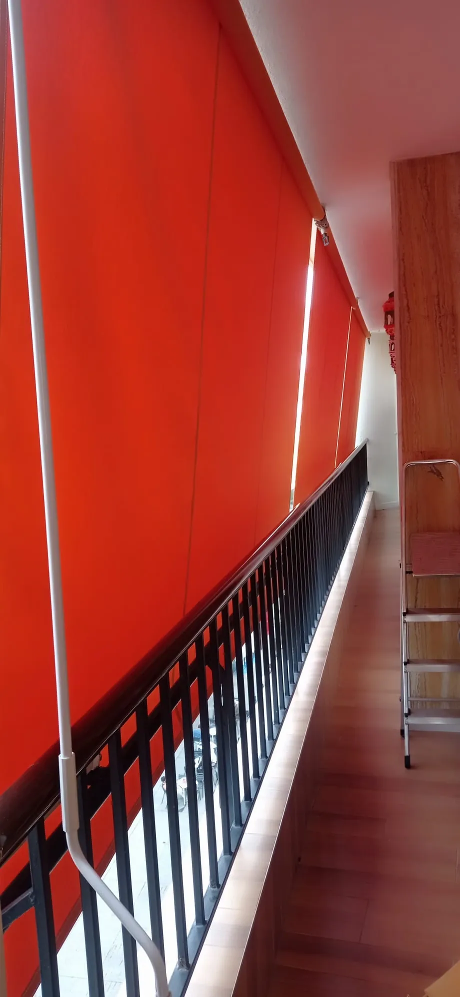 Toldo de balcón con lona roja junto a una barandilla